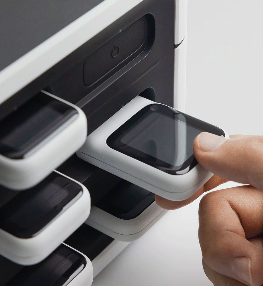 从多层充电座中取出一块白色边框智能手表的场景