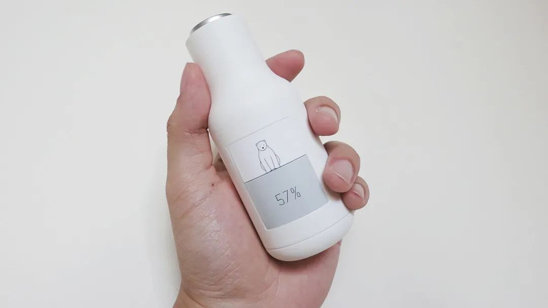 手握显示小熊图案和57%电量的白色设备