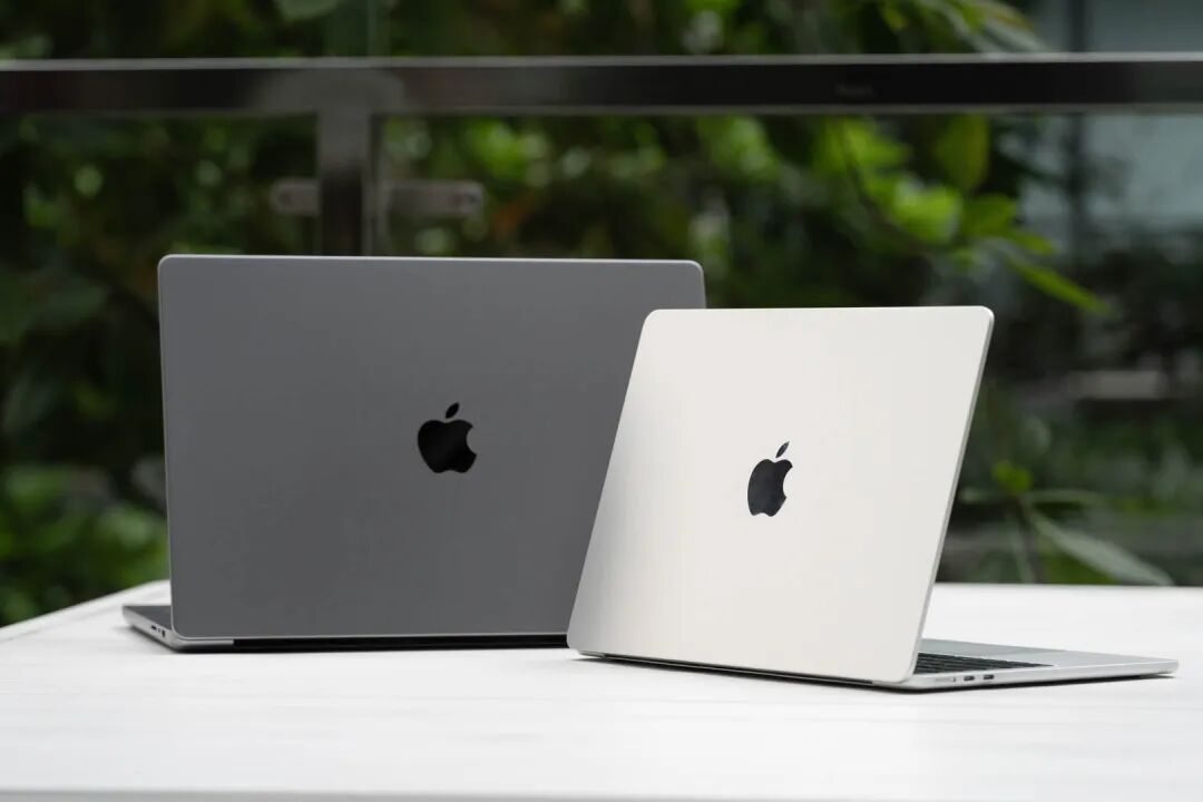两张银色与深灰色MacBook背面展示苹果Logo