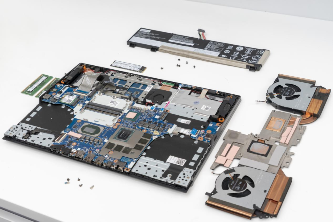 拆解的笔记本电脑主板、散热模组、风扇和电池组件俯拍图
