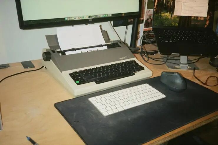 老式电动打字机、显示器与无线键鼠组成的工作台