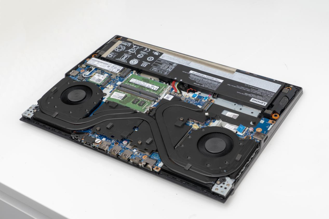 拆开的联想笔记本电脑内部结构，可见主板、双风扇散热模组和电池