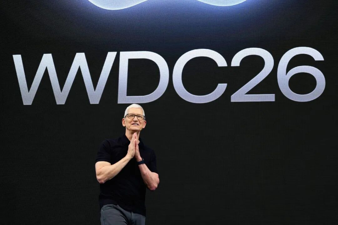 WWDC 2026 大会现场,演讲者站在舞台前,身后大屏幕显示活动标志
