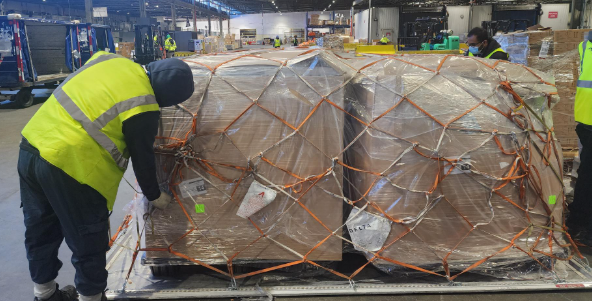 仓库作业场景：工作人员处理托盘上的大型纸箱货物