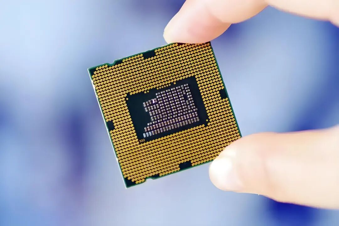 一只手捏着布满金色焊点的CPU芯片