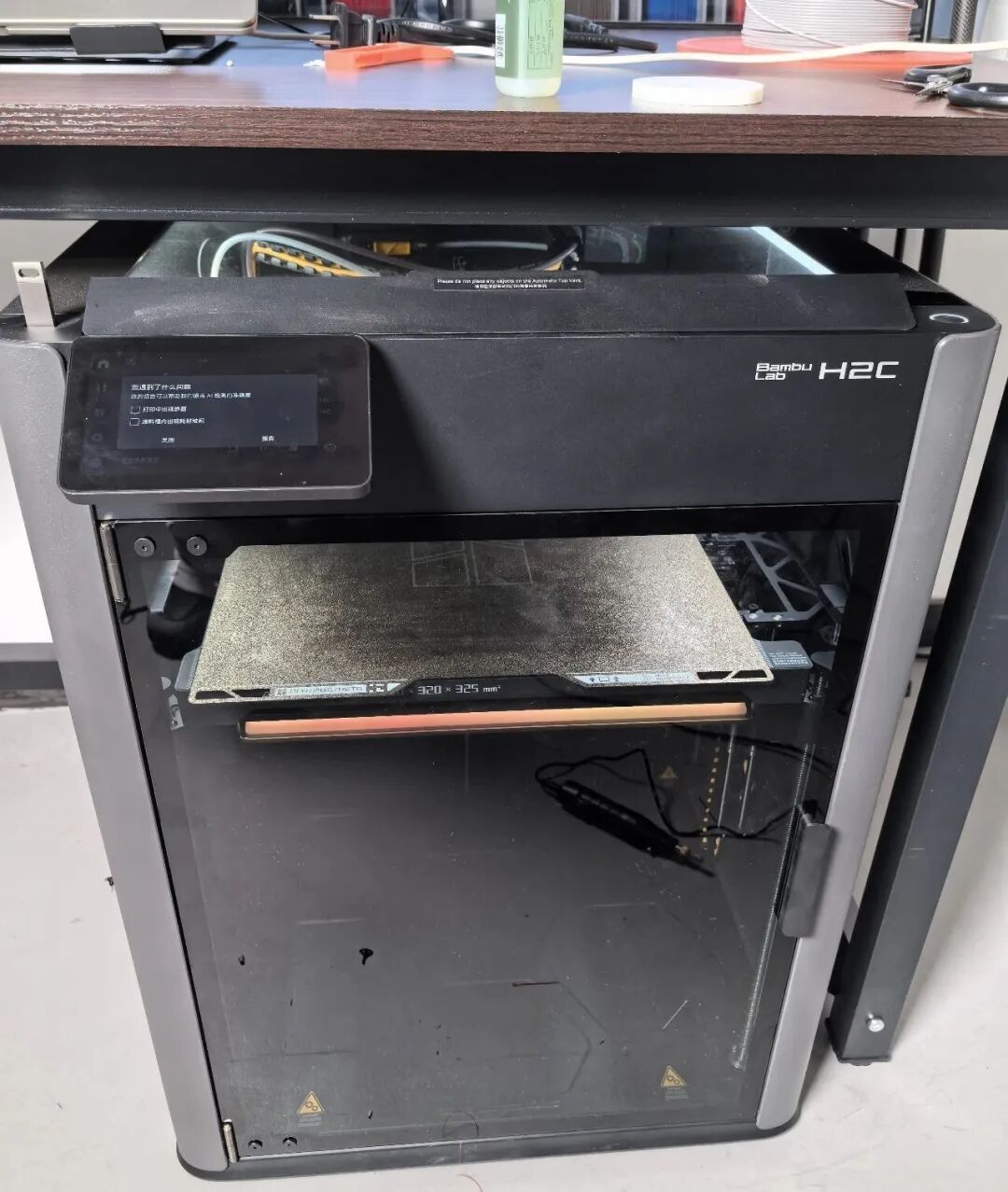 Bambu Lab H2C型号3D打印机放置在桌下的照片