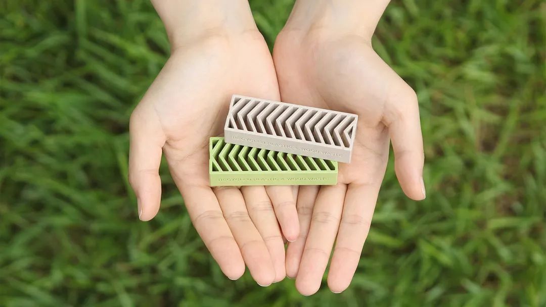 双手捧着绿色与灰色的环保积木产品