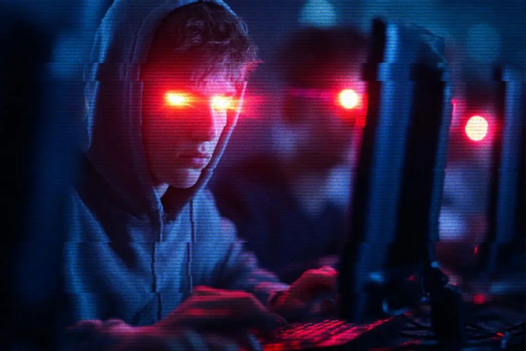 一名眼中闪烁红光的年轻人坐在电脑前的合成图像