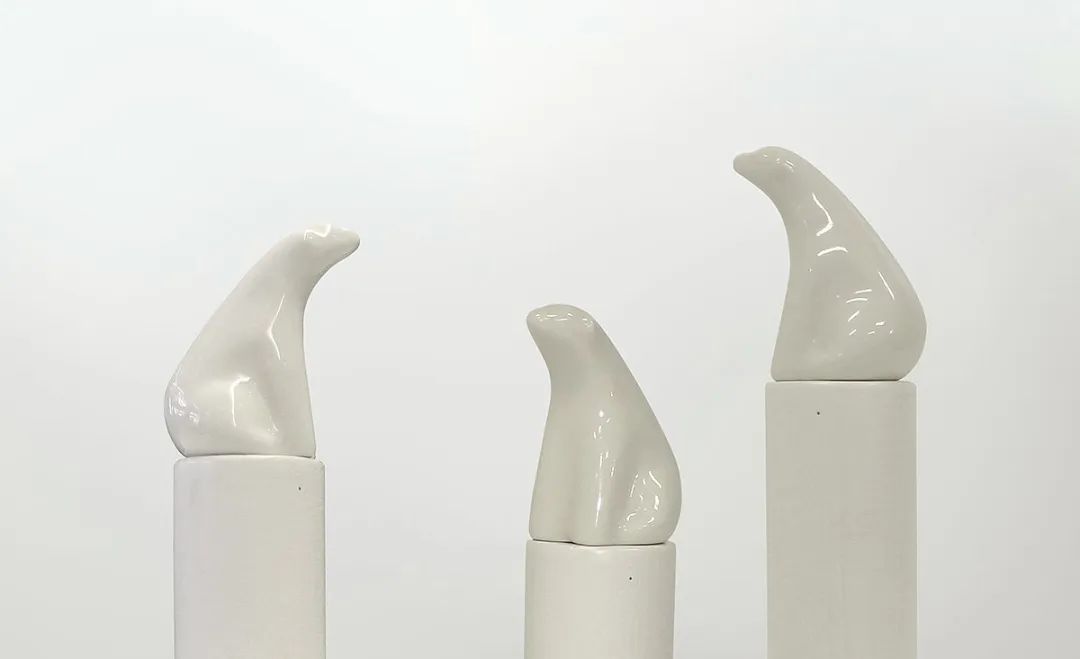 放置在圆柱形底座上的三件白色抽象鸟形陶瓷雕塑