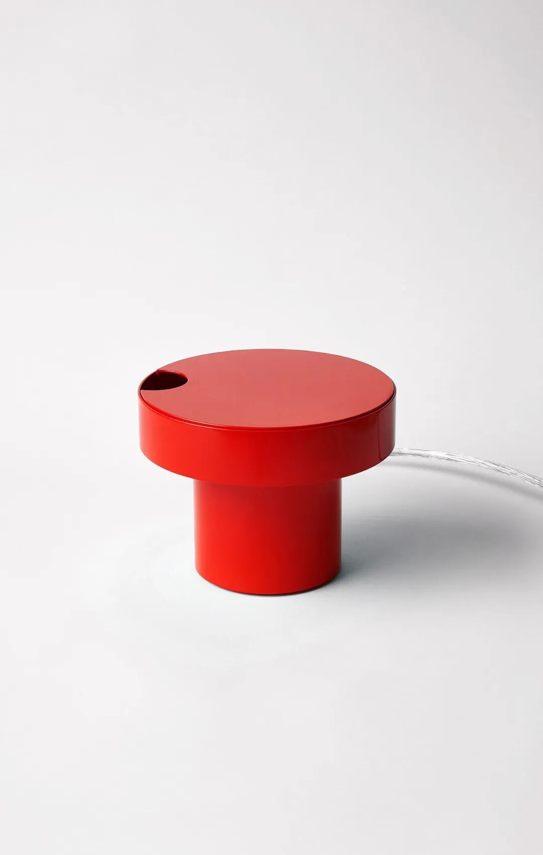 一个红色的圆柱形现代设计台灯，顶部为圆形盖子
