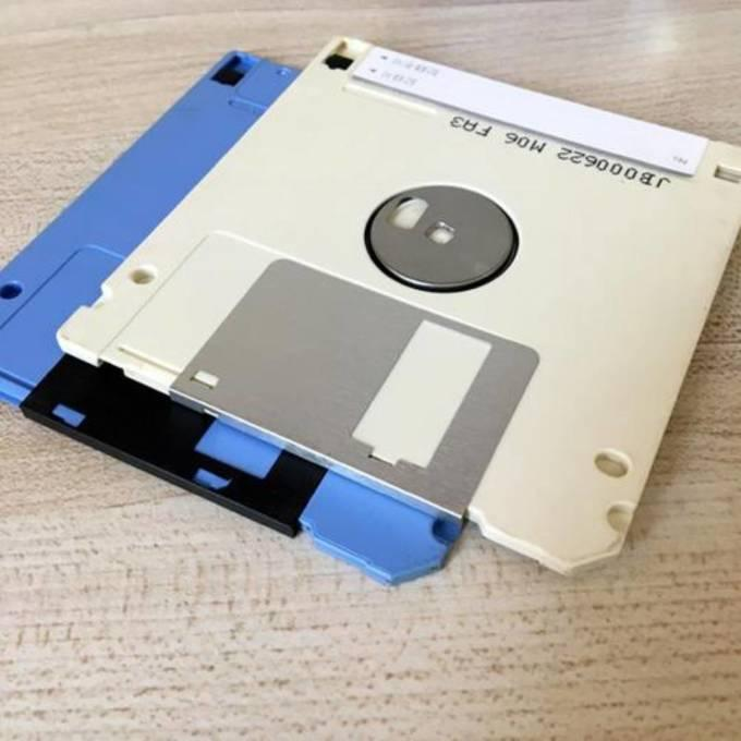 一张3.5英寸软盘与多张不同颜色的软盘叠放在木质桌面上