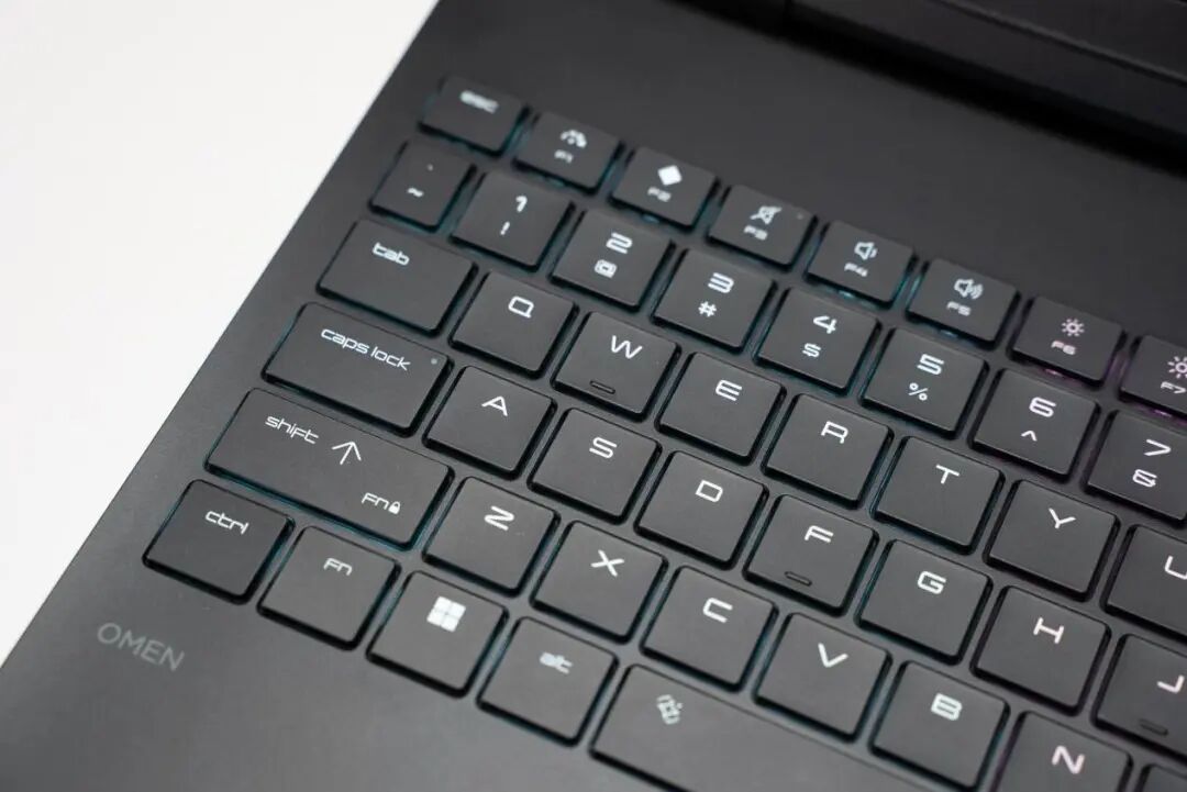 黑色笔记本电脑键盘特写，可见OMEN标识与蓝紫色渐变背光