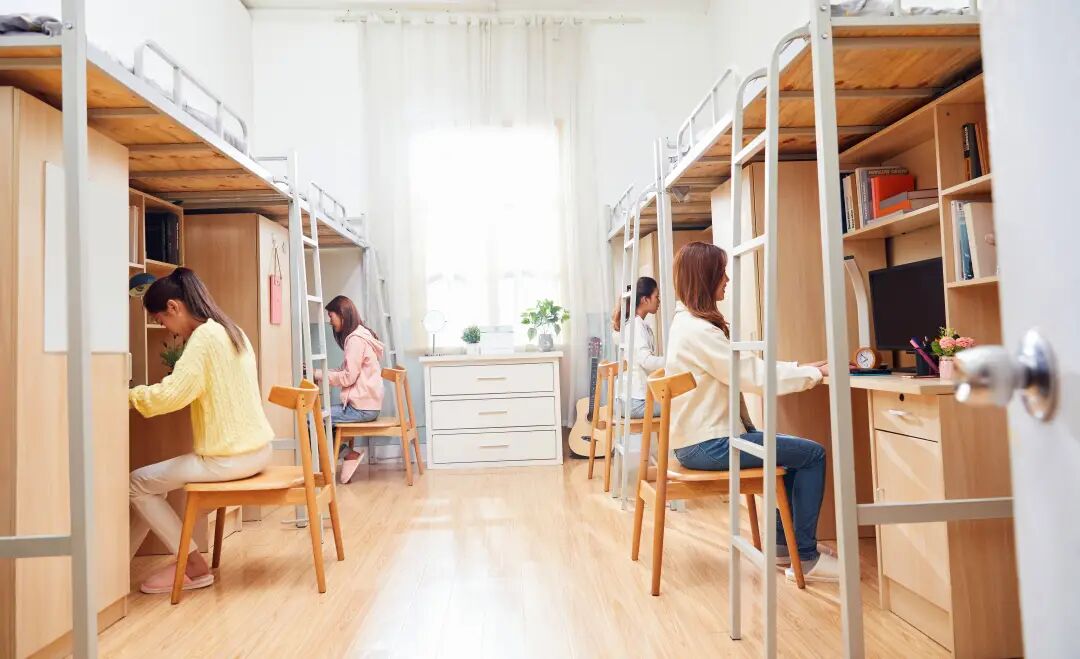 大学宿舍内部实景照片，显示上下铺和书桌