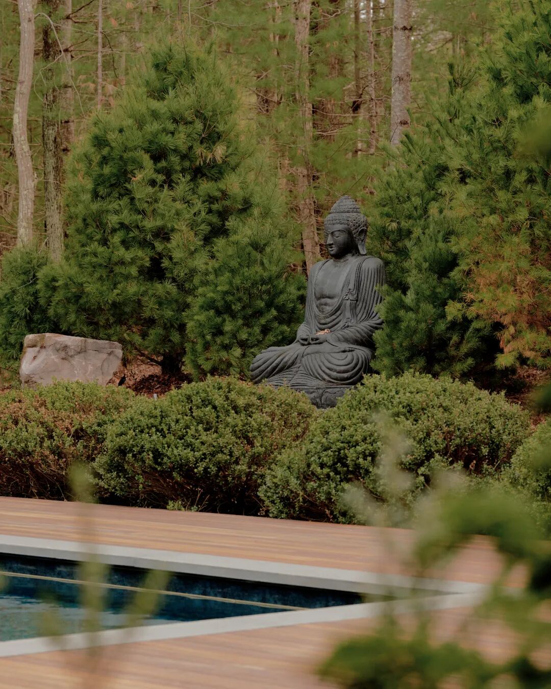 泳池边宁静的坐佛雕像