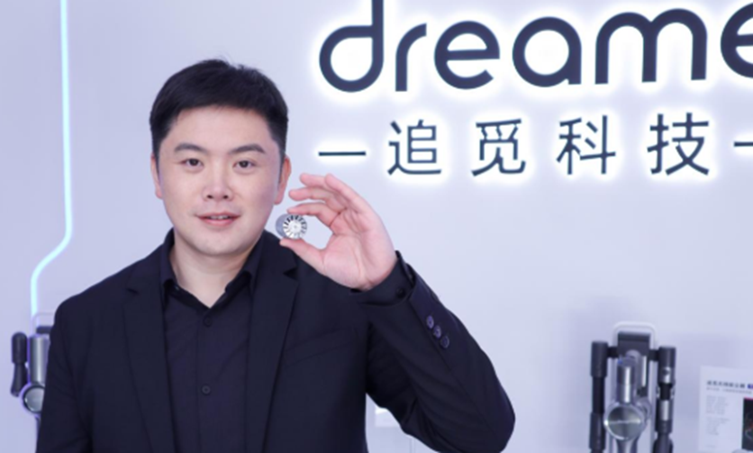 追觅科技创始人俞浩身穿黑色西装，手持银色圆形物件，背景有发光的“dream”字样和中文标语“—追觅科技—”