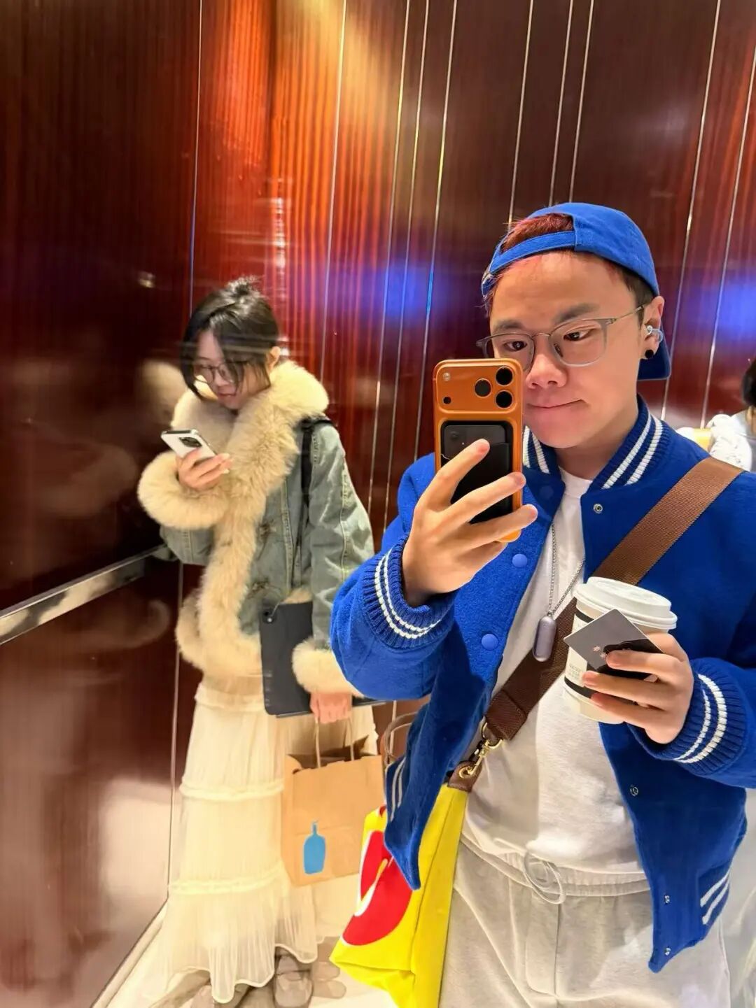 一位身处电梯内的男子自拍，镜中反射出其同行女子