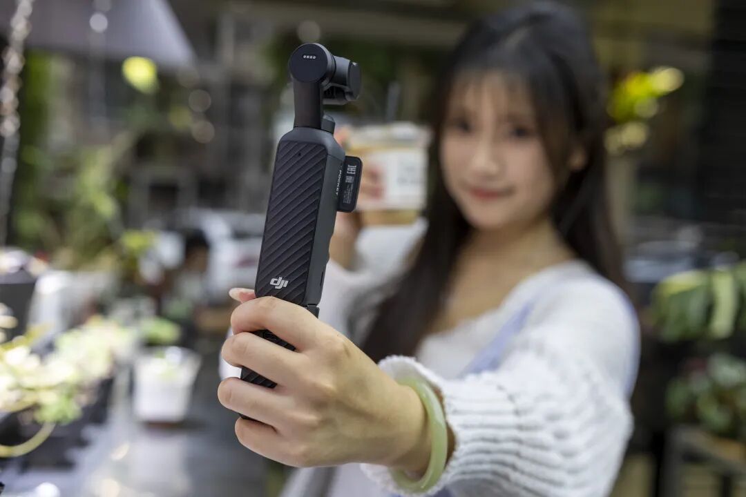 一名年轻女性手持大疆DJI Osmo Mobile 7手持云台稳定器