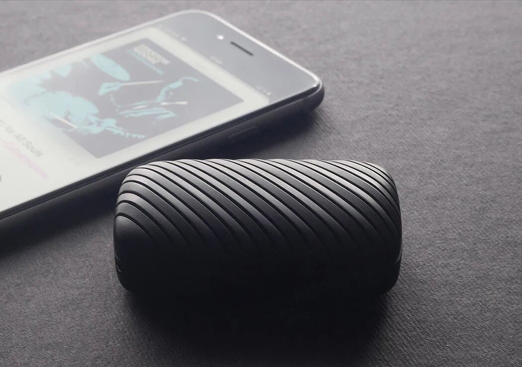 一张展示黑色条纹设计无线耳机充电盒与智能手机并置的特写照片