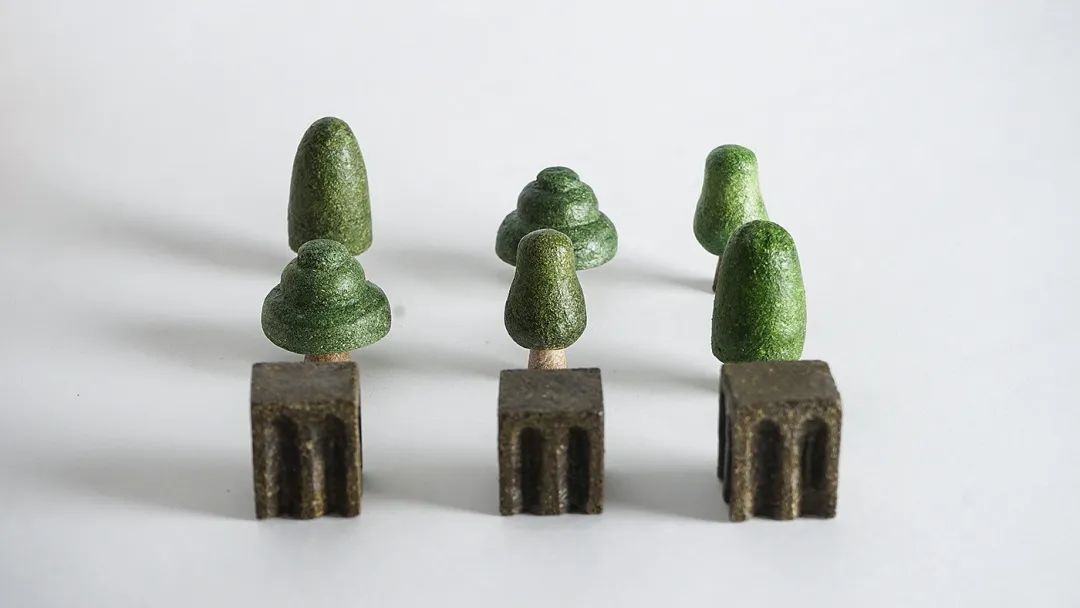 三组绿色微型树状模型与深灰色底座