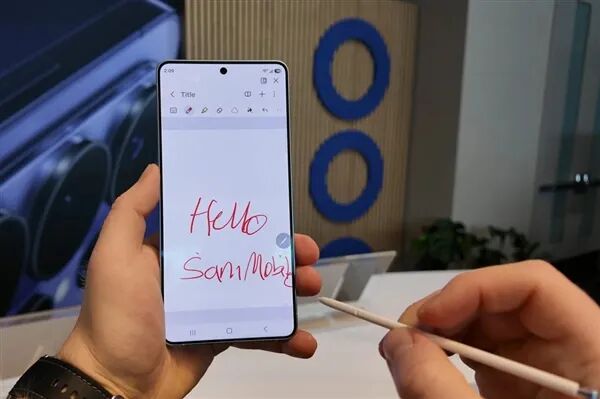 一只手握手机并使用触控笔在屏幕上书写“Hello SamMoy”