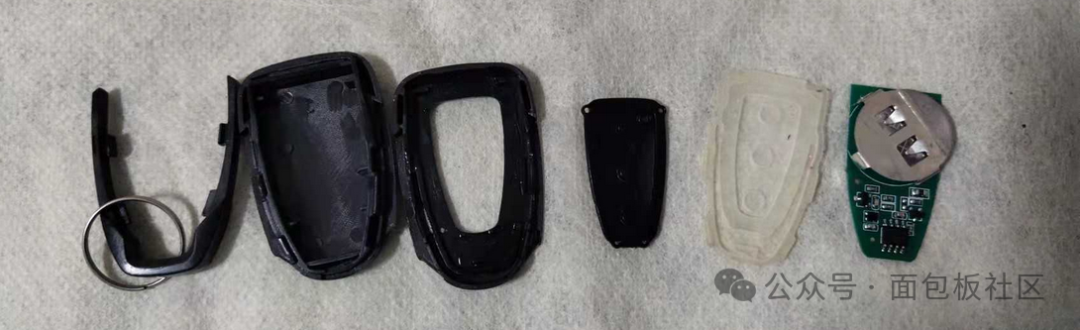 拆解后的遥控器部件，包括外壳、电路板、纽扣电池和按键垫