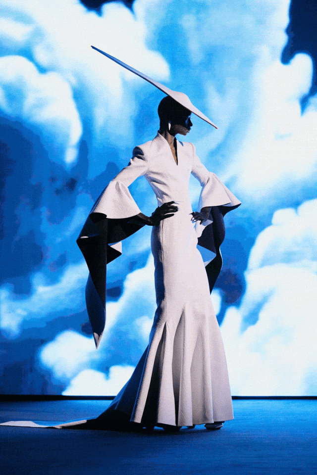 四张时尚摄影图拼接展示：第一张为白裙黑袖、戴长尖帽的模特立于蓝白云雾背景前；第二张为红裙配珍珠装饰、戴红帽的模特在日落海景前摆姿；第三张为金箔质感连体衣、戴金属面具与尖刺装饰的模特立于黄绿色背景中；第四张为黑底金星亮片长裙、头戴黑色薄纱面纱的模特背影，背景为暖黄云霞。整体呈现高定时装秀或艺术摄影风格，强调戏剧性造型与强烈色彩对比。