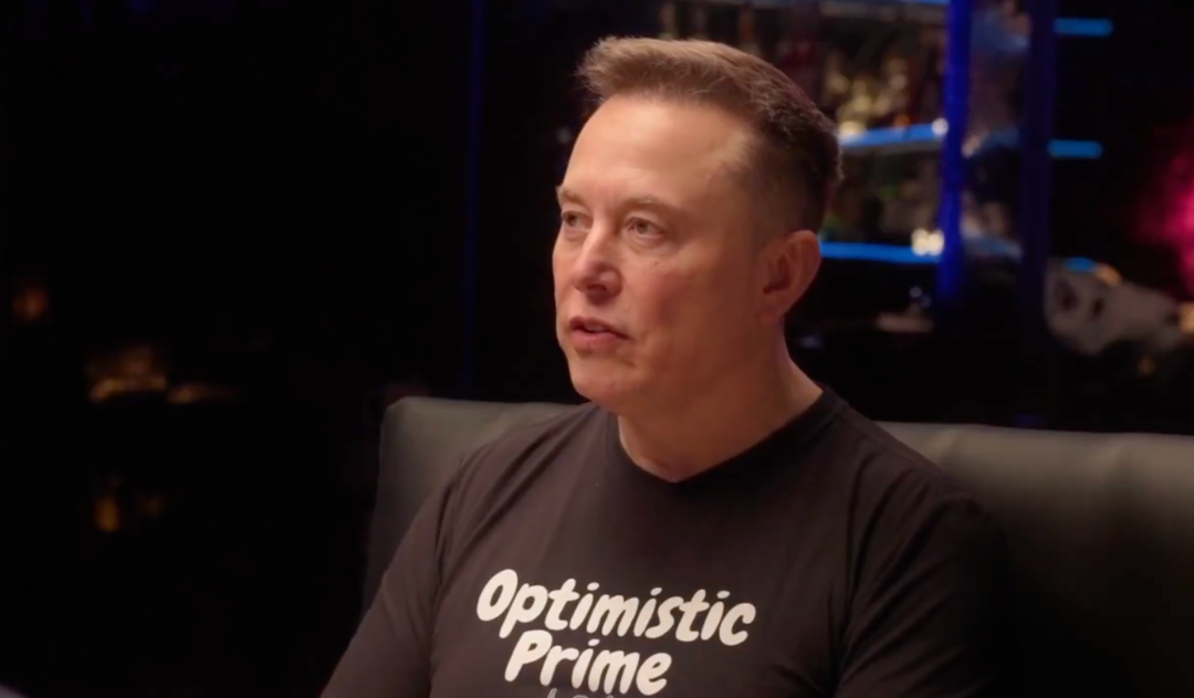 马斯克在访谈中，身着印有‘Optimistic Prime’的黑色T恤