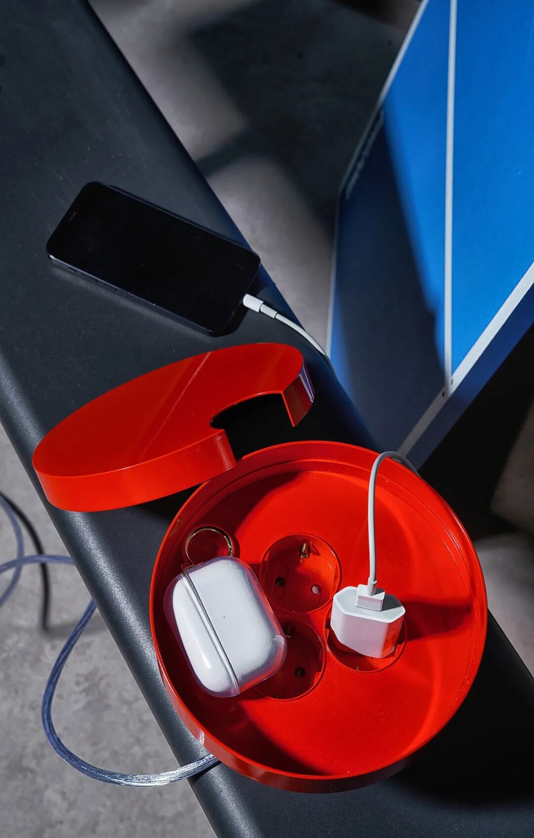 一个红色的圆形充电收纳盒，放置在黑色桌面上