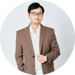 一位戴眼镜的男士，身穿棕色西装外套和白色衬衫，背景为圆形白色边框，整体风格简洁专业。