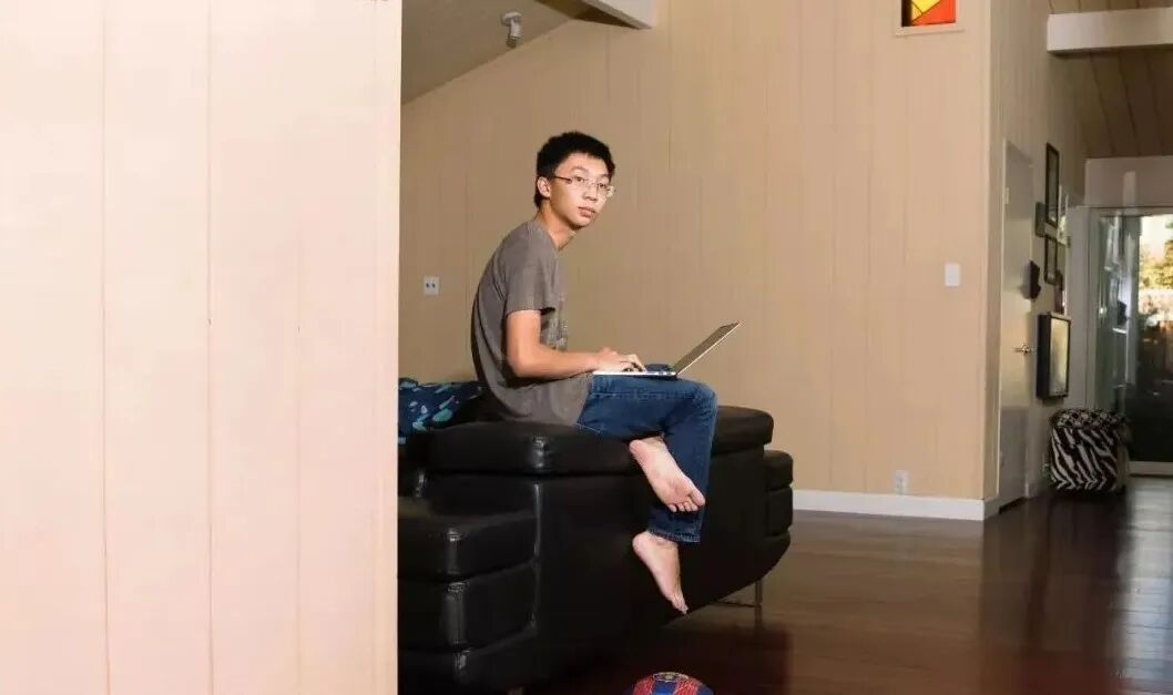 Kevin Frans坐在沙发上使用笔记本电脑