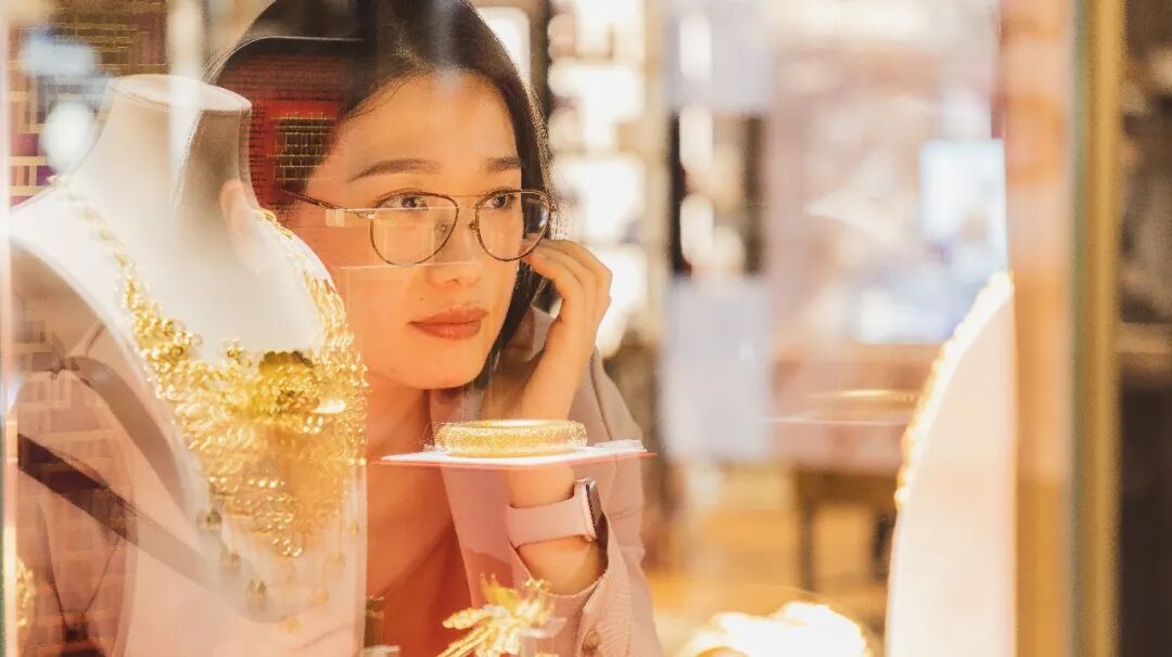 女性在珠宝店前凝视黄金饰品