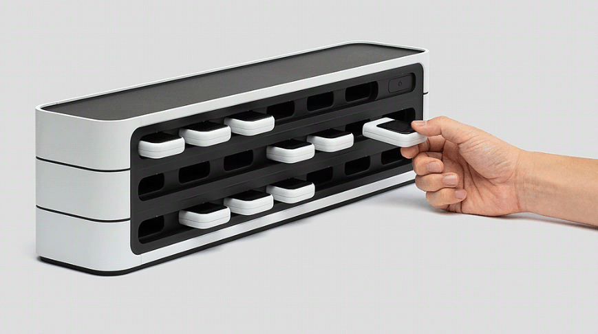 从黑白相间的收纳架中取出白色方形电子设备