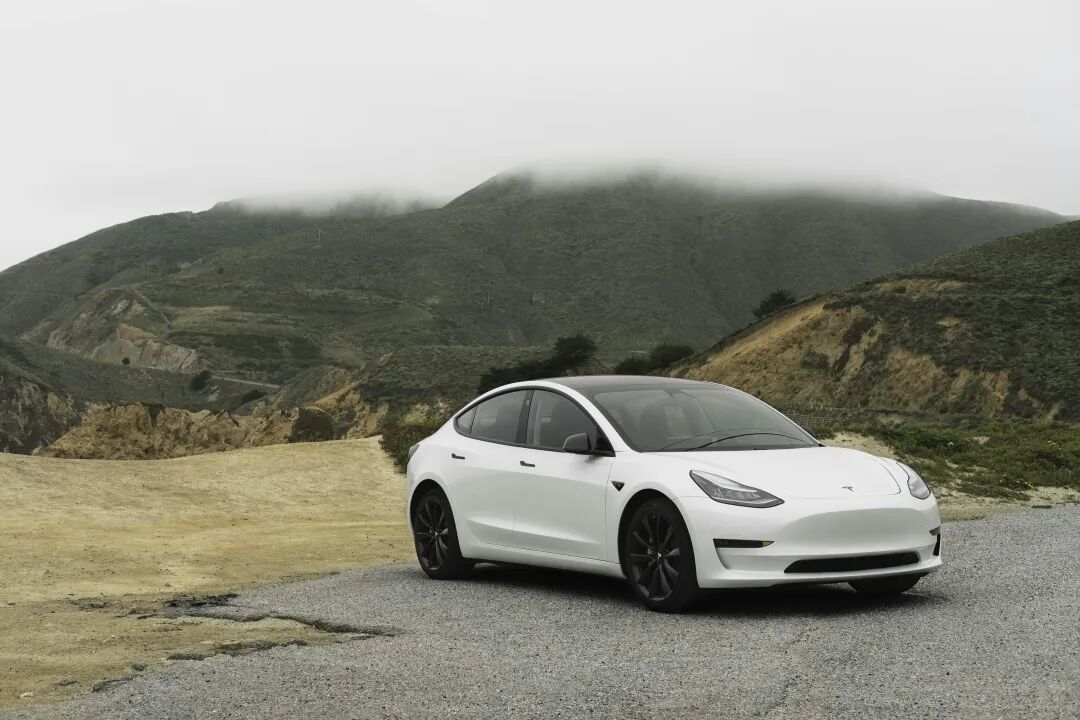 白色特斯拉Model 3停在山间公路