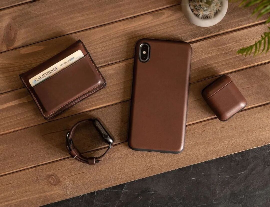 俯拍视角下，木质桌面上摆放着一套棕色皮革配件