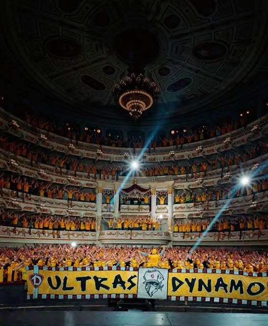 坐满黄色观众、悬挂“ULTRAS DYNAMO”横幅的剧院内部