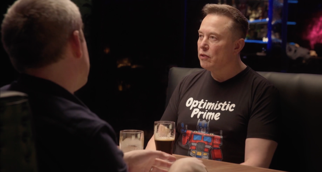 马斯克身穿“Optimistic Prime”T恤与人交谈