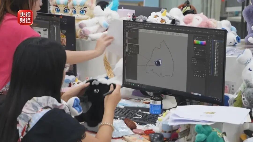 央视财经截图中工作人员对照屏幕设计毛绒玩偶的角色形象
