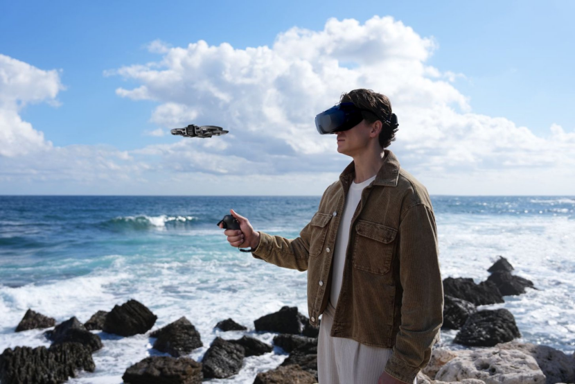 男子佩戴VR头显站在海边礁石上,空中悬浮着一艘科幻风格飞船