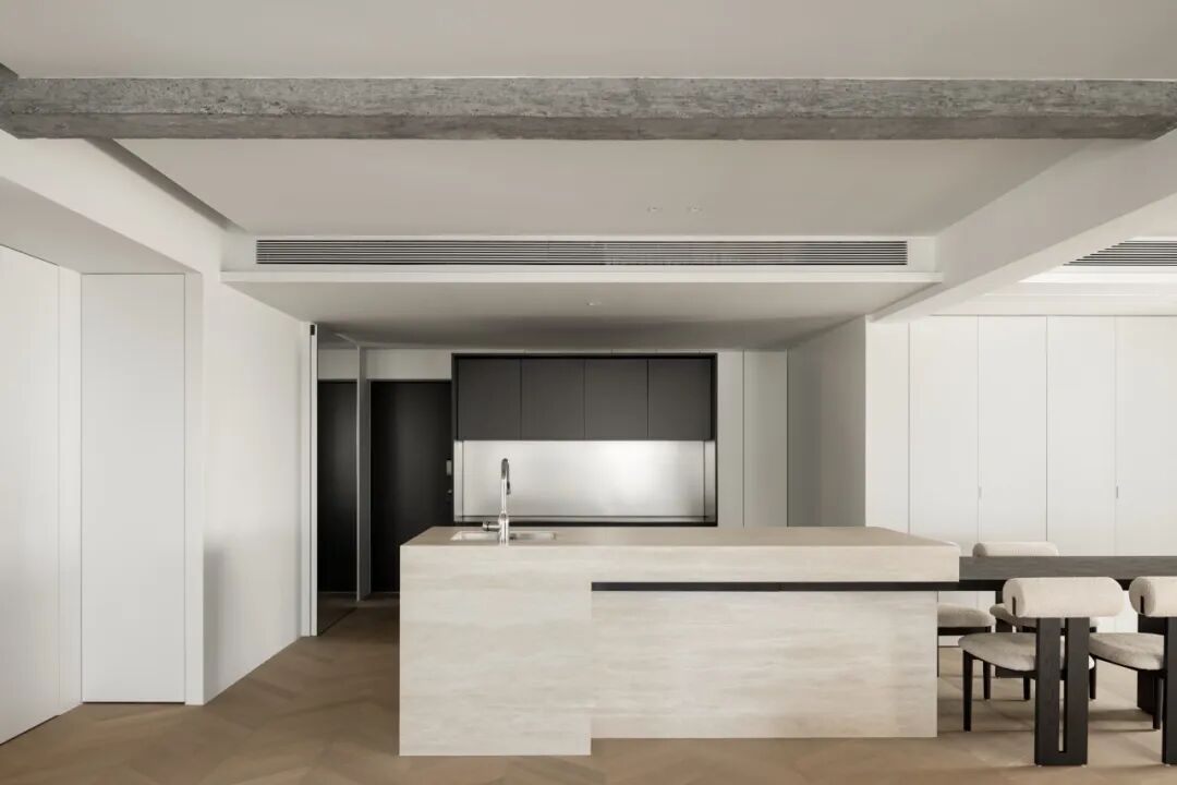 开放式餐厨区，浅色石材岛台与黑色木饰面