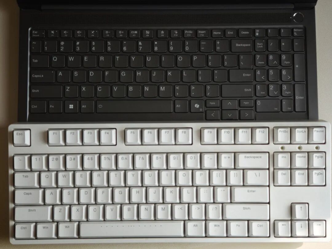 笔记本键盘与白色机械键盘的叠放对比图