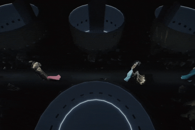 俯视视角下的黑暗场景，多个大型深色圆柱形结构分布于画面中，顶部有小孔排列。前景底部有一个发光的环形结构，边缘呈亮白色。画面中有数个穿着飘逸长裙的人物在空中或悬浮状态下漂浮移动：左侧人物身着黑衣配粉红色下摆；中间偏左人物穿白金渐变长裙，裙摆展开如羽翼；右侧人物穿蓝绿色长裙，姿态舒展；最右侧还可见部分黑衣人物。整体氛围幽暗神秘，似为科幻或奇幻风格的舞台表演或动画片段。