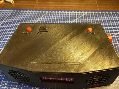 安装在3D打印外壳内的设备正面，顶部有HACK按钮和开关