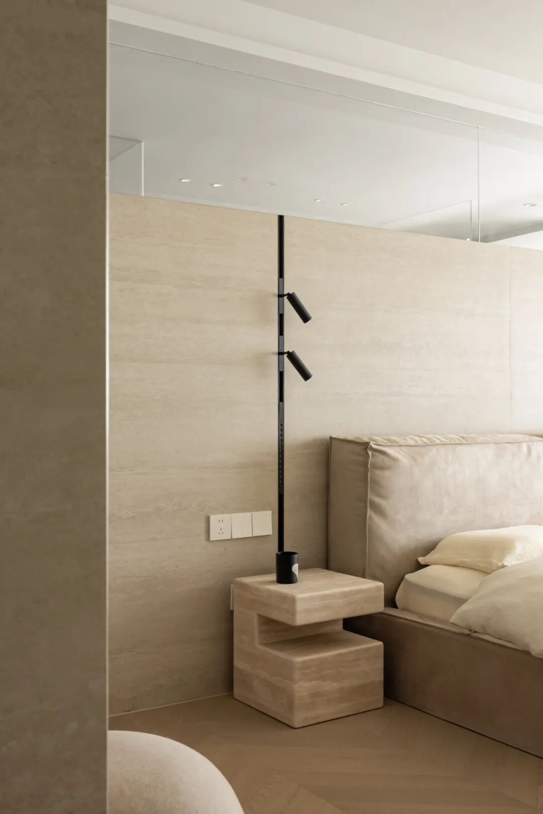 卧室床头一角，石材床头柜与落地灯