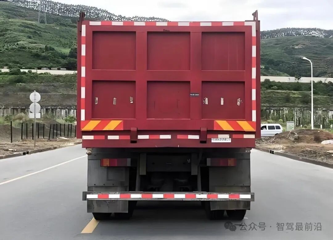 一辆红色自卸卡车的后视图,展示了大型车辆对视野的遮挡