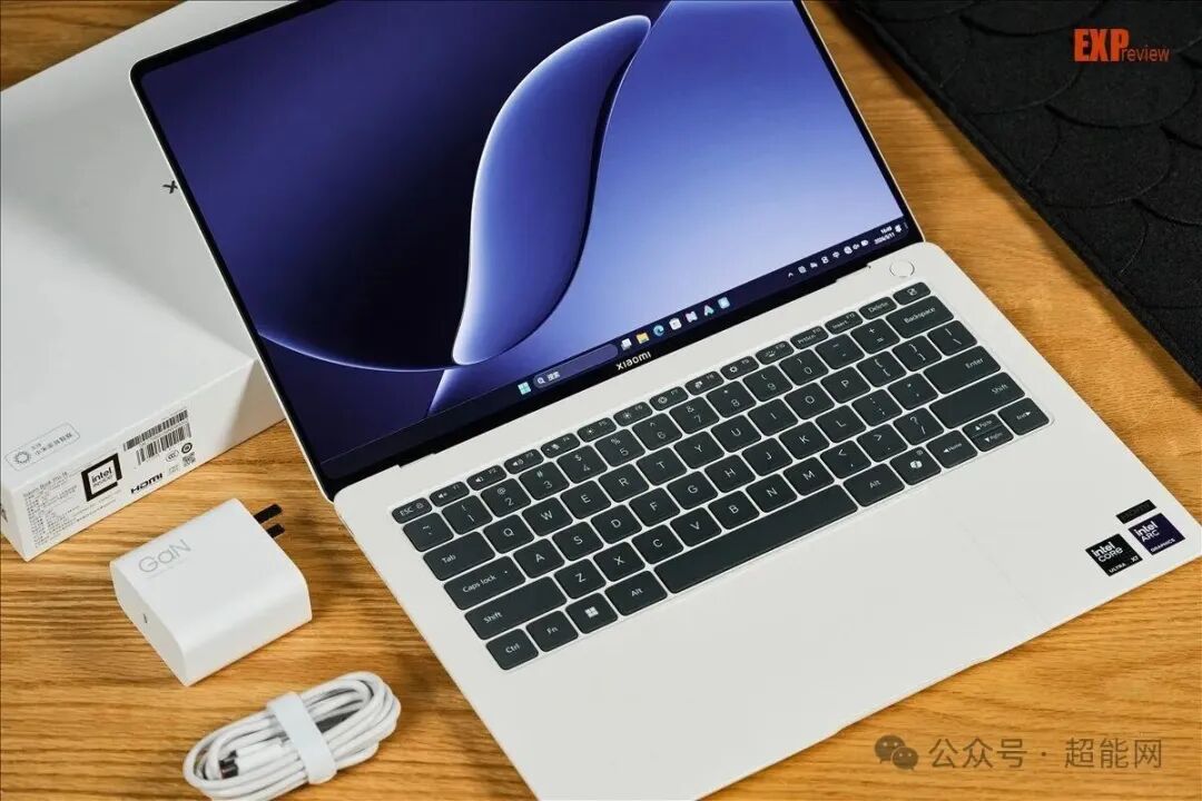 小米笔记本打开放置在桌面,旁边是充电器和数据线