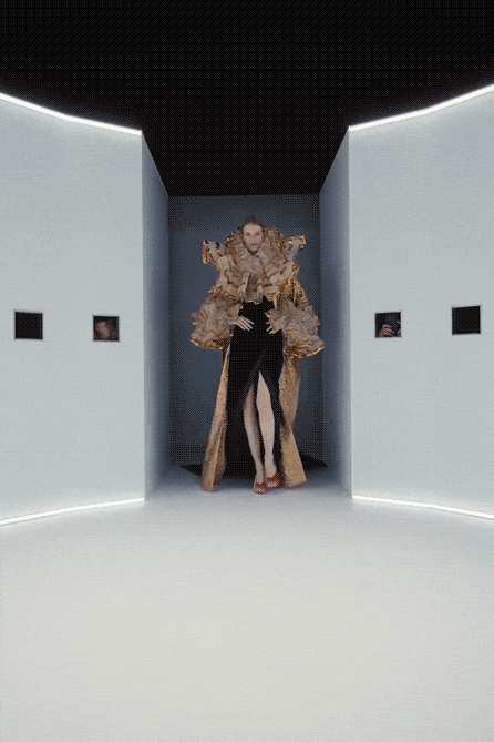 一位模特身着极具视觉冲击力的时装，在现代极简风格的白色展厅中走秀。服装主体为黑色高开衩长裙，搭配一件巨大、层叠、立体的金色褶皱袖饰，材质轻盈飘逸，带有金色亮线装饰。展厅墙壁与地面为纯白色，顶部及墙角嵌有发光灯带，墙面挂有数幅小型方形画作。从不同角度拍摄：正面全身照显示模特正对镜头；特写镜头聚焦于金色褶皱面料的纹理细节；俯视视角展示模特在圆形光圈区域内的动态姿态；最后一帧为全黑画面，可能为转场或结束。整体氛围科技感与艺术感并存。