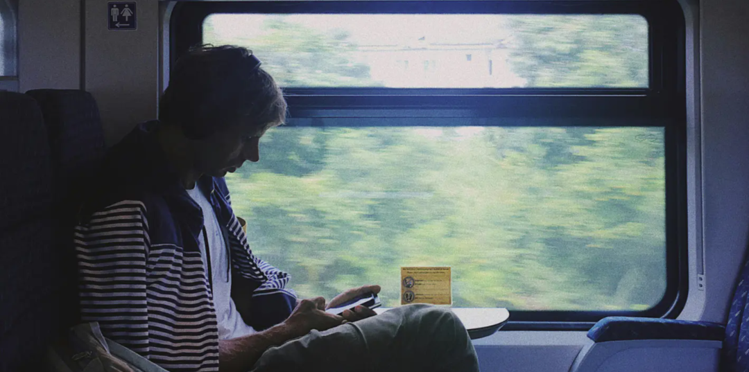 一名男子在行驶的火车上专注玩手机