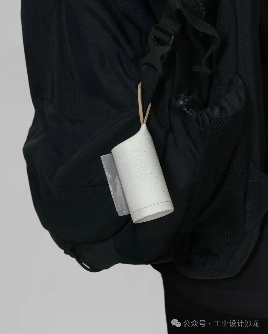 挂在黑色背包侧面的白色圆柱形垃圾袋