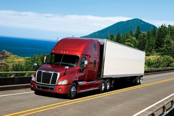 红色卡车行驶在景色优美的沿海公路上