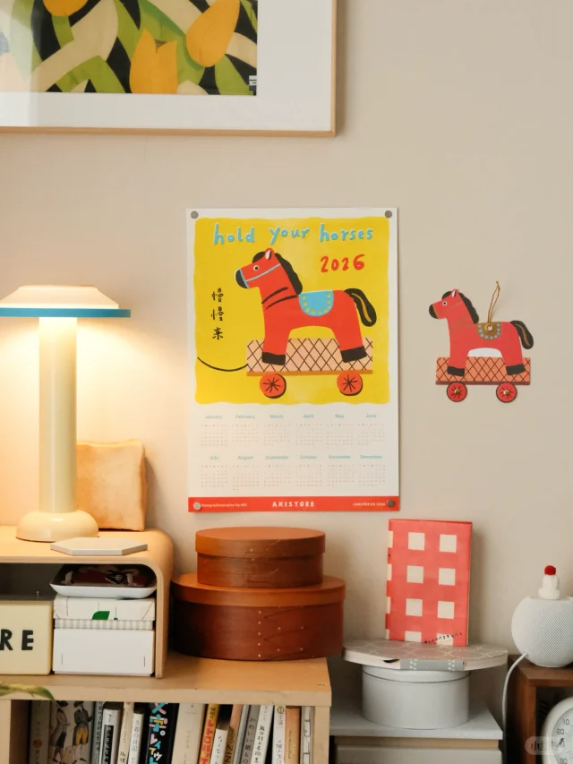 日历挂于墙面：“hold your horses 2026”，旁边“慢慢来”，书架上同款木马装饰
